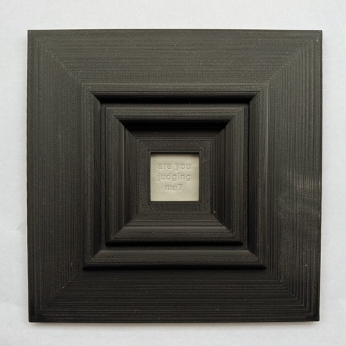 Original, minimalist, hand-embossed grey art card featuring the fun message ‘are you judging me?’ demonstrating the scale of the black oversized 3d printed frame