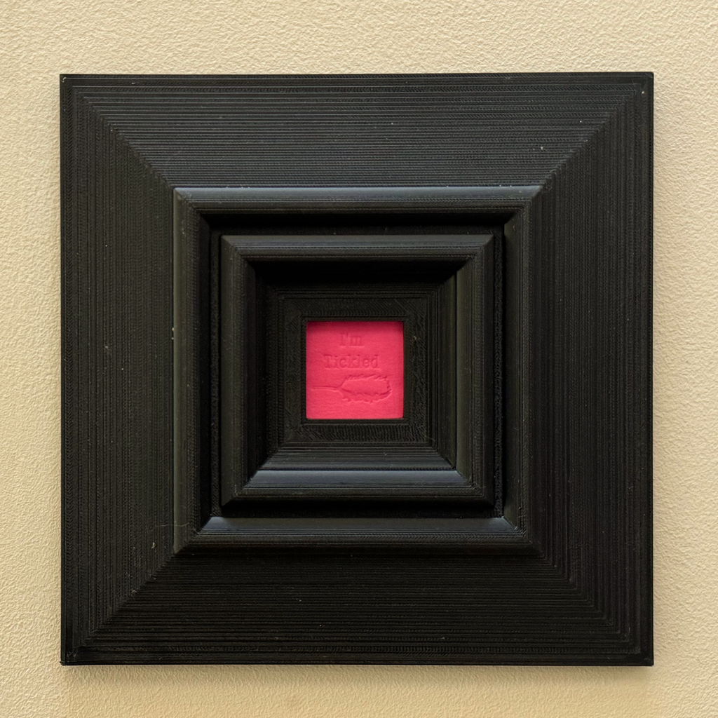 Original, minimalist, hand-embossed pink art card featuring the fun message ‘I’m Tickled’ demonstrating the scale of the black oversized 3d printed frame